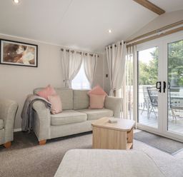 A living room with sofas coffee table and glass doors opening to a balcony at Pams Place in Crantock
