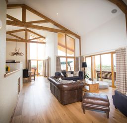 A living room with leather sofas wooden beams and large windows at Aurae in Cawdor near Inverness