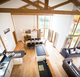 A large open living space with kitchen sink and counter dining table with chairs and sofas near large windows at Atlas Cawdor near Inverness