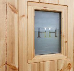 A wooden door with a small frosted glass window with the letters HH at Shepherds Hut in Garthorpe near Scunthorpe