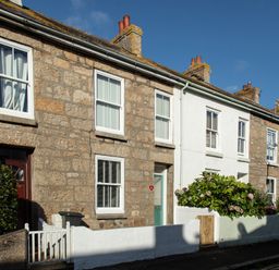 A row of stone and white terraced houses with small front gardens on a street at 11 Belgravia Street in Penzance