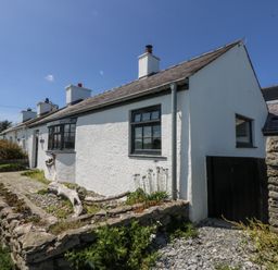 A cottage with a stone wall and garden at Bwthyn Y Swnt in Moelfre