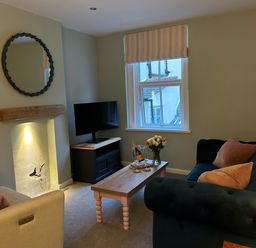 A sitting room with two sofas a coffee table a television a round mirror and a window at Secret Garden 34C Clarence Street in Dartmouth