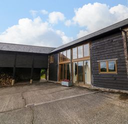The exterior of a building with wooden cladding stone walls and large windows at Hunstone Barn in South Molton