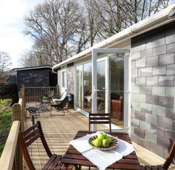 A wooden deck with outdoor chairs and a table with green apples at Treetops in Caernarfon