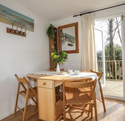A dining area with a wooden table and chairs next to glass doors leading to a balcony at Treetops in Caernarfon