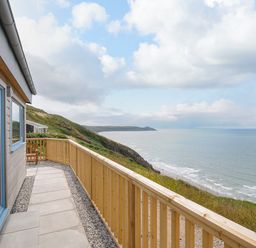 A balcony with wooden railing overlooking a coastal cliff and the sea at Solana Whitsand Bay