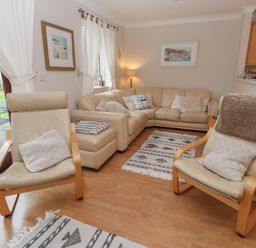 A living room with beige leather chairs a beige sectional sofa and patterned rugs at Alberts Den in Falmouth