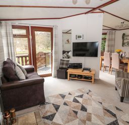 A living room with a sofa a TV and a dining table near Evergreen Lodge in Felmoor Holiday Park near Felton