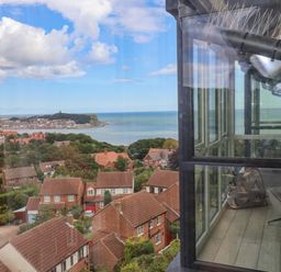 View of a residential area with houses trees and a coastline visible through a window at The Penthouse in Scarborough