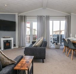 A living room with sofas a wall mounted TV and dining table with chairs at Lakeside 20 in Warton near Carnforth