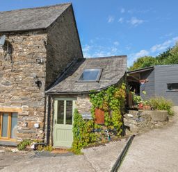 A stone building with a green door and plants at Little Coombe Trehunist near Liskeard