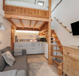 A living room with a kitchenette and staircase at Little Coombe in Trehunist near Liskeard