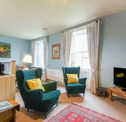 A living room with two armchairs and a TV at Riverbank Cottage in Alnmouth