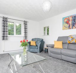 A living room with a gray sofa and blue armchair with yellow cushions at The Old Forge in Trerulefoot