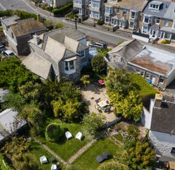 An aerial view of houses and a garden with trees and outdoor furniture at Ayr Farmhouse in St Ives