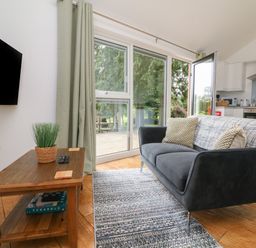 A living room with a gray sofa and wooden coffee table near sliding glass doors at Jasmine Bydown near Barnstaple
