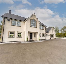 A large white house with multiple windows and a black front door with small green bushes on either side in a paved driveway at Parc Y Deri in Rhos-y-garth near Aberystwyth