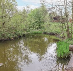 A small pond with trees and grass around and a wooden fence and a gazebo in the background at 24 Lakeside Drive in Felton