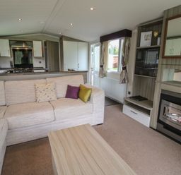 A living room with a sectional sofa and pillows next to a fireplace and kitchen at Swan in Shobdon