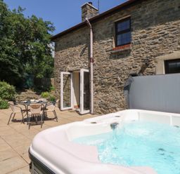An outdoor patio with a hot tub and table with chairs at Felin Gogoyan Tregaron