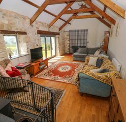 A living room with wooden beams stone walls sofas and a television at Bryn Nante Morvil near Maenclochog