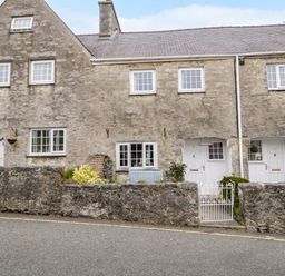 Stone cottages with white doors and windows and a small garden with a bench behind a low stone wall at 3 Moranedd Moelfre