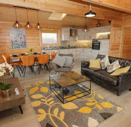 A living room with a sofa armchair coffee table dining table chairs and kitchen at Height End Farm Log Cabin Rossendale near Bacup