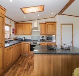 A kitchen with wooden cabinets a countertop island and appliances at Three Views Lodge in Whitsand Bay Fort Holiday Village