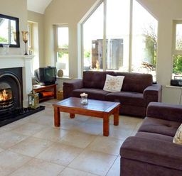 A living room with two sofas a wooden coffee table a fireplace and a television at Bluebell Cottage in Spanish Point County Clare