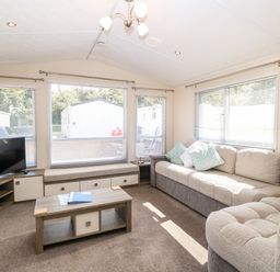 A living room with a large sofa coffee table television and windows with blinds at Hazell Thorne Hideaway in Fritton