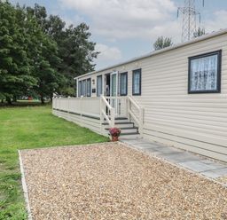 A caravan with stairs and a railing beside a gravel and grass area at Stanley's Lodge Foxburrow Hang in Belton Norfolk