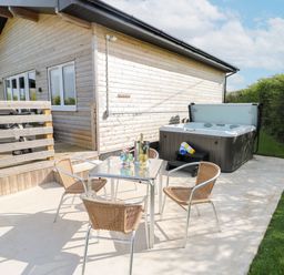 An outdoor area with a hot tub and seating at Heritage Retreat in Monknash