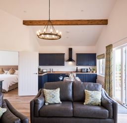 A living room with a sofa and kitchen area at Monks Rest in Monknash