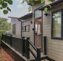Exterior view of a modern house with open door and black railing at Serendipity R11 Fallbarrow Park near Bowness-On-Windermere