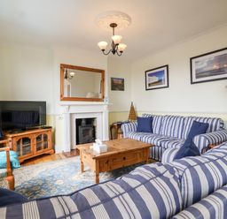 A living room with striped sofas a wooden coffee table a fireplace and a television at The Pink House in Felixstowe Suffolk