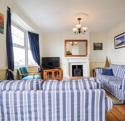 A living room with blue striped sofas a wood stove and a television at The Pink House in Felixstowe Suffolk