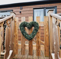 A wooden fence gate with a heart-shaped green wreath at Pine Lake View in Coniston View 3 Carnforth