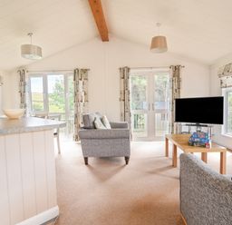 A living room with two grey sofas a wooden coffee table with board games and a television at The Hideaway in Eype