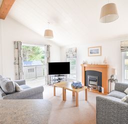 A living room with two grey sofas a wooden coffee table a TV and a fireplace at The Hideaway in Eype