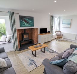 A living room with two sofas a coffee table and a wood stove at Turning Tide in Beadnell
