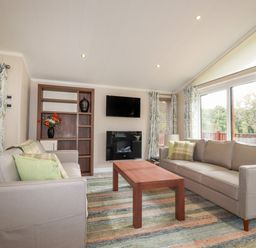 A living room with two sofas a wooden coffee table and a wall-mounted TV at Haven Lodge in Bossiney Bay near Tintagel