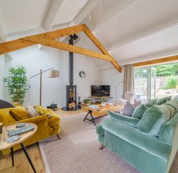 A living room with green and yellow sofas a wood stove and a wooden coffee table at The Granary in Davidstow near Camelford