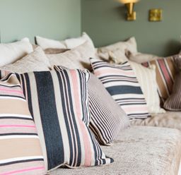 A close-up of a sofa with multiple striped and plain cushions in a room at Casa Formentera in Scarborough