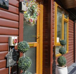 An entrance with a welcome sign and topiary plants at Ruskin Lodge, Langdale 16, White Cross Bay near Windermere