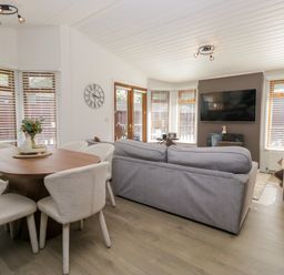 A living room with a sofa and dining area at Ruskin Lodge, Langdale 16, White Cross Bay near Windermere