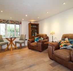 A living room with two leather armchairs and a small dining table with two chairs at The Studio at Dan y Garn in Newport Pembrokeshire