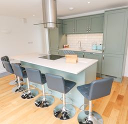 A kitchen with a large island and five bar stools at James Place in Falmouth
