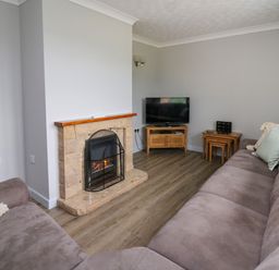 A living room with two sofas a fireplace a television on a wooden stand and nesting tables at Ashdale in Bwlch-y-sarnau near Rhayader