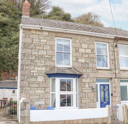 Stone house with bay window blue door and outdoor seating area at Crab Pot Cottage in Porthleven